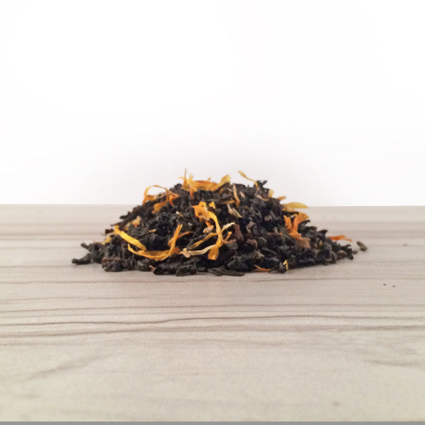 Pile of Marigold and  darjeeling tea on white tile,  Dembones Tea