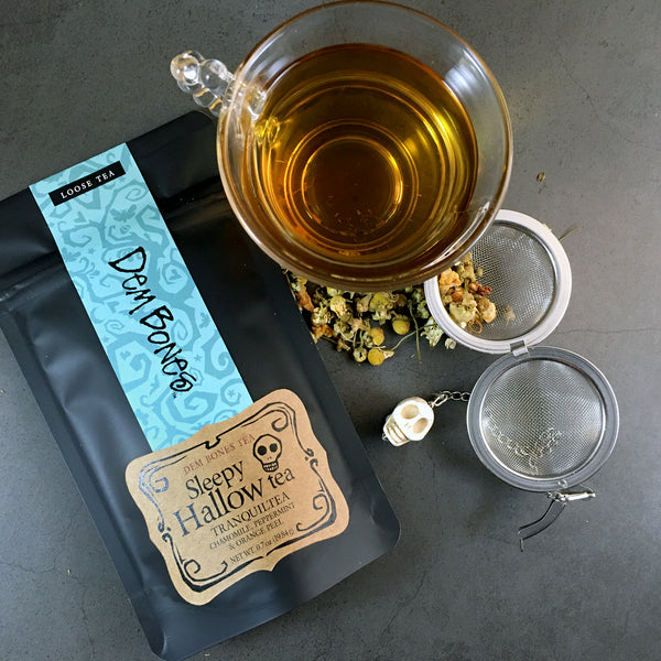 Sleepy hallow Tranquilitea, Black foil bag of Tea on dark background, clear tea cup of tea with tea ball, chamomile mint  tea
