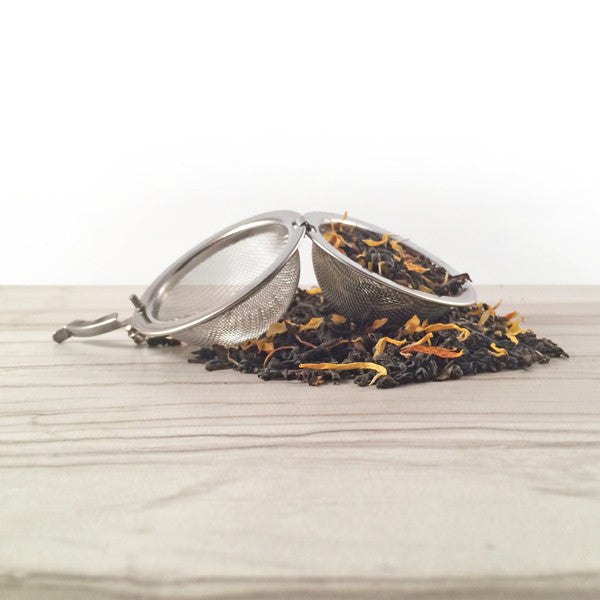 Darjeeling tea with marigold in tea ball, White tile background -Dembones Tea