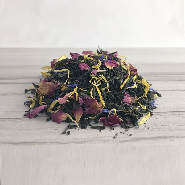 Mound of Earl Grey Tea with Rose Marigold and Cornflower Petals on light tile background